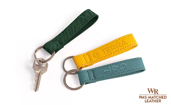 Three faux leather key rings in green, yellow, and blue, embroidered with custom brand.