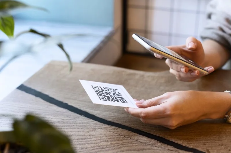 Person scanning QR code card with smartphone at trade show