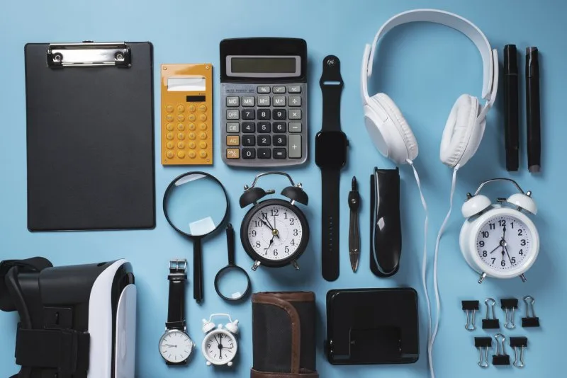 Flat lay of tech accessories like headphones, smartwatches, clocks