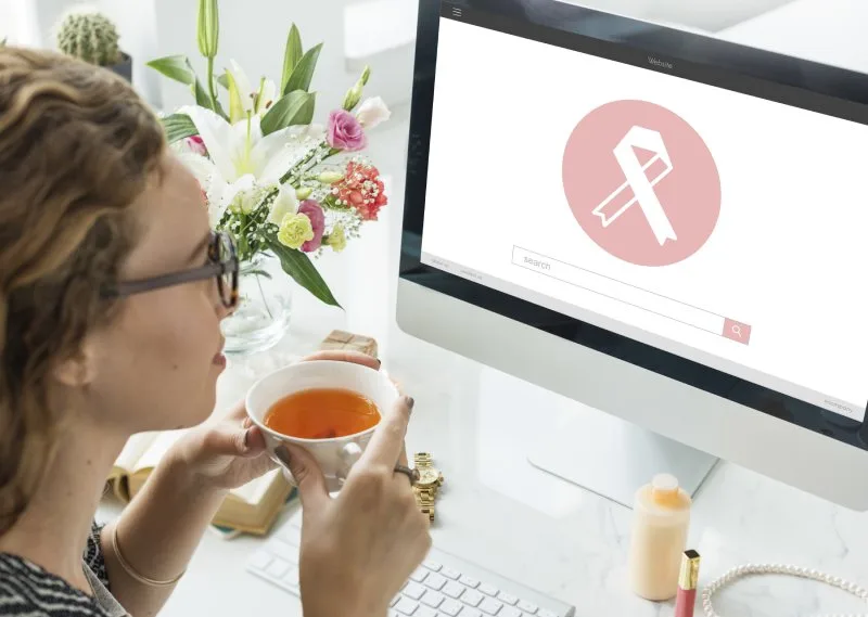 Marketing professional researching breast cancer awareness giveaway ideas on computer while supporting awareness campaigns.