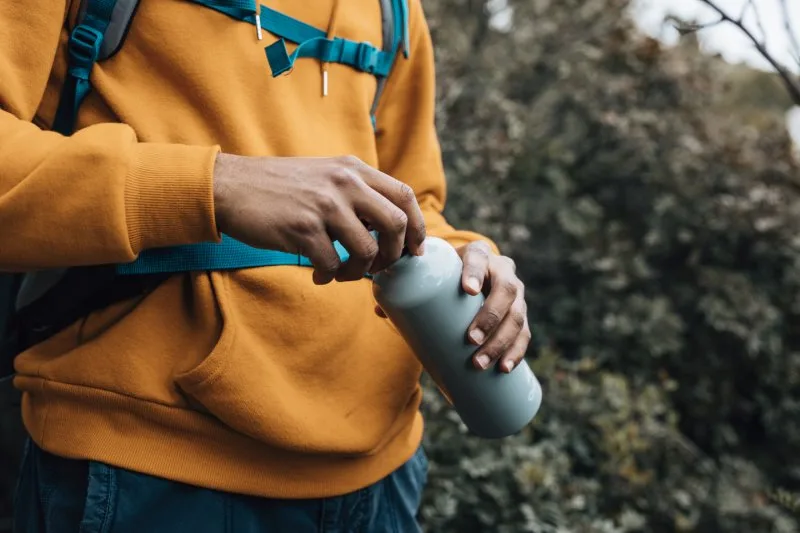 A person holding a hydroflask, an example of a practical hydration gift idea for employees.