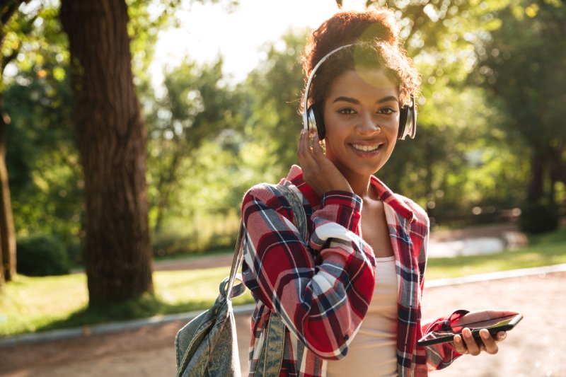 College student wearing headphones and a backpack using technology promotional products, ideal for career fair recruiting