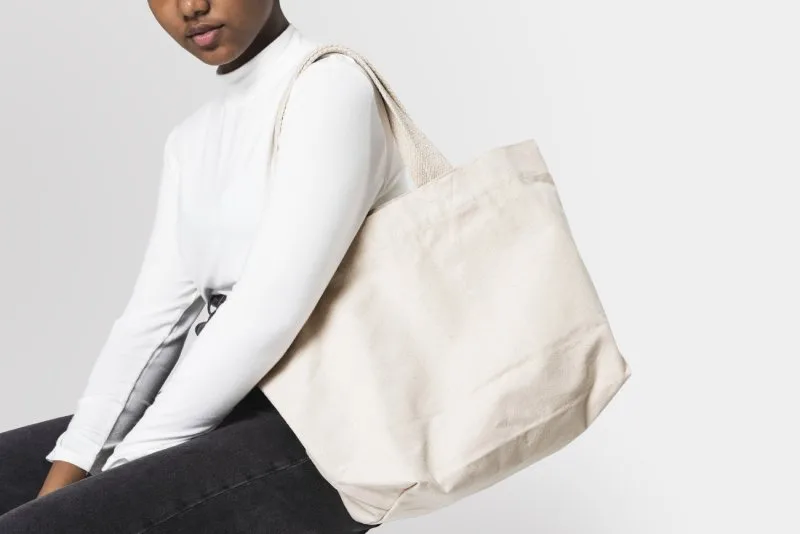  Woman holding a minimalist beige tote bag showcasing stylish and practical promotional swag.