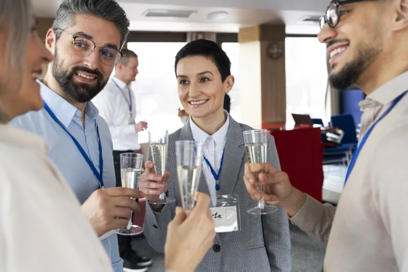 Trade show professionals in business attire, networking with drinks, emphasizing the importance of dressing professionally and comfortably.