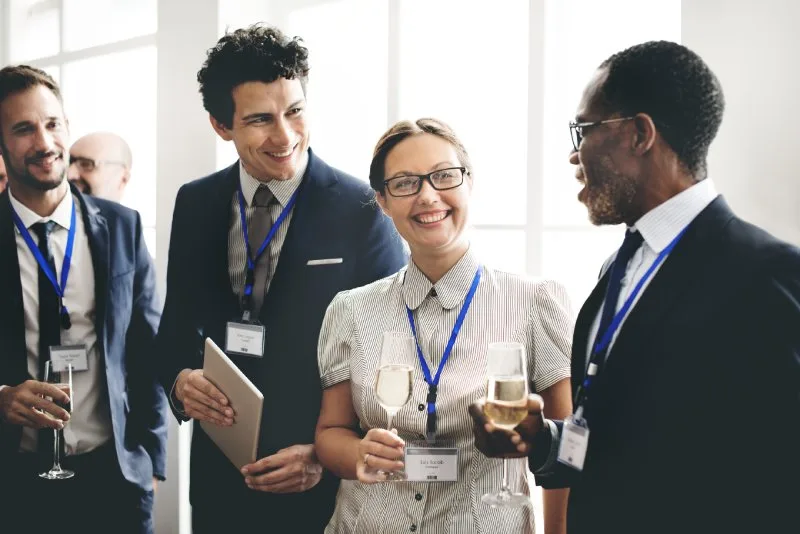 Business professionals mingling with drinks at an event, demonstrating the key networking strategy of watching for conversation openings