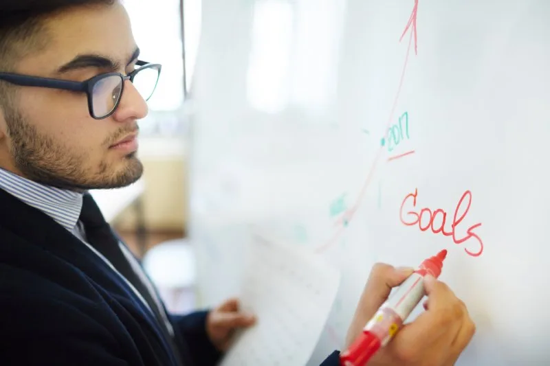 Marketing manager writing SMART goals on a whiteboard to measure long-term  trade show effectiveness