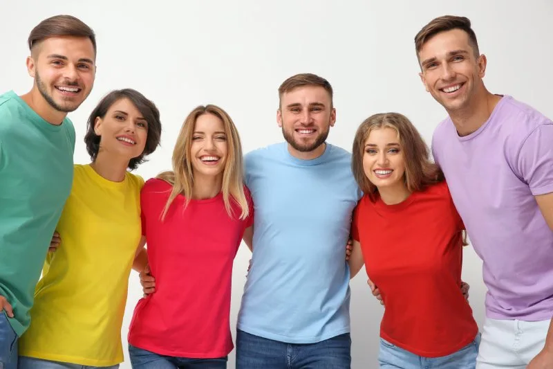 Happy team wearing colorful branded t-shirts in red, yellow and blue for company events