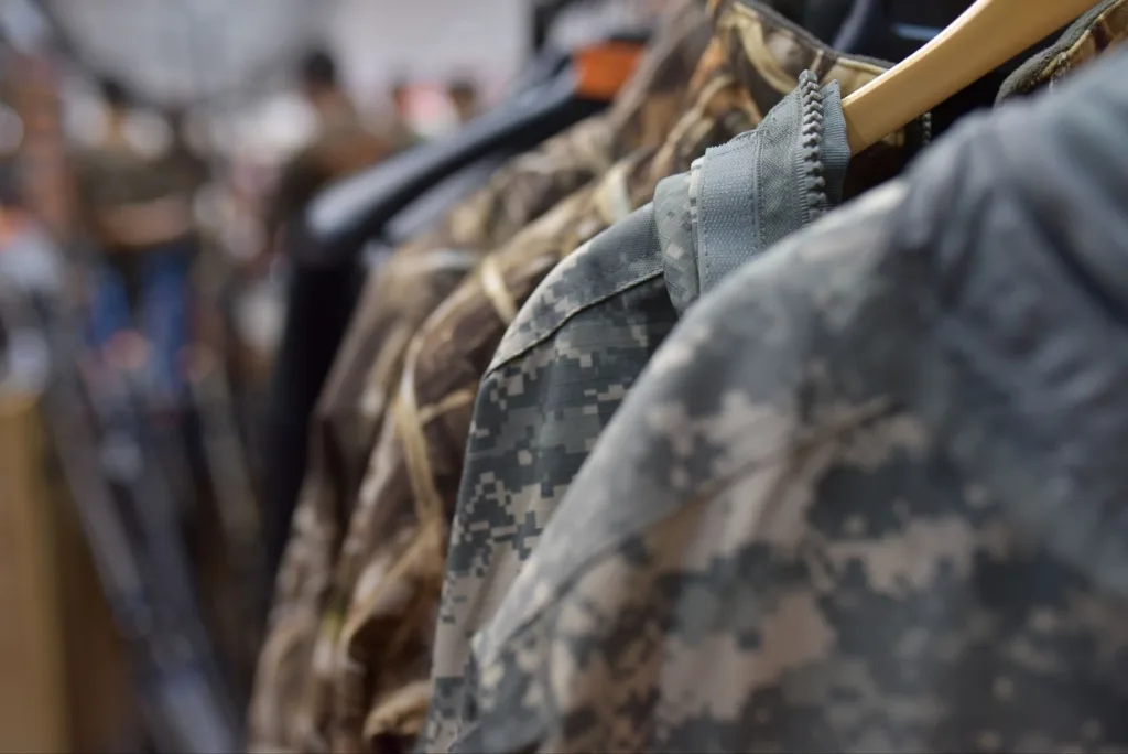 Close up of various custom camo shirts and jackets hanging on a retail clothing rack.