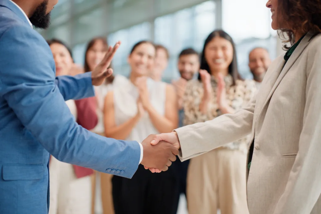 Employee shaking hands in front of crowd after promotion.