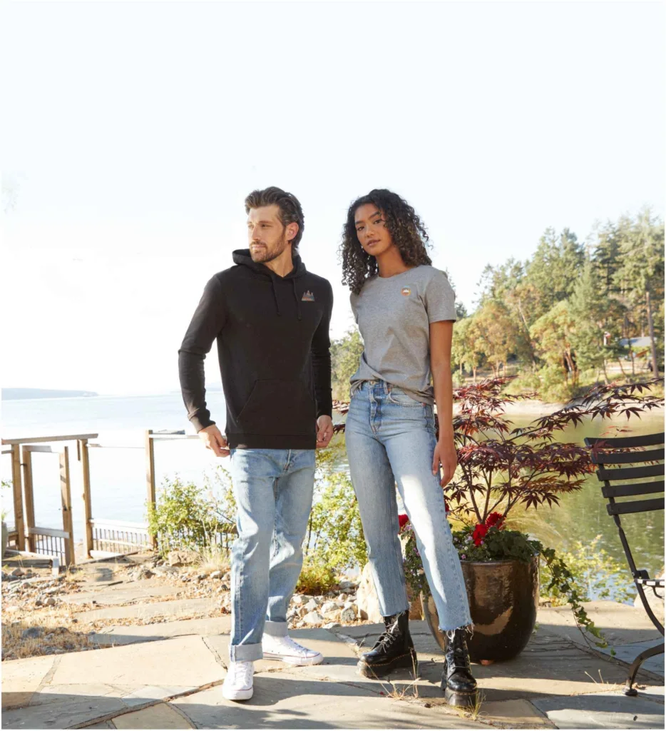 Man and woman stnading in front of lake wearing branded apparel with left chest logo placement.