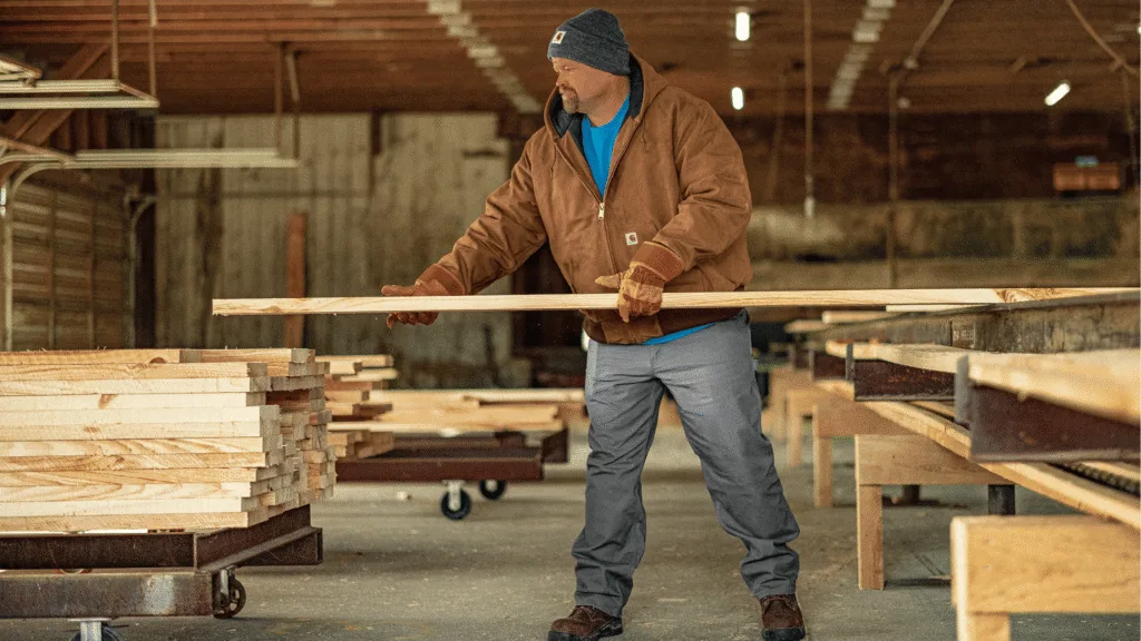 Man wearing brown custom Carhartt jacket while working in woodshop.