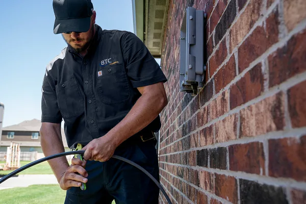 Man workin on cable line wearing logo uniform shirt
