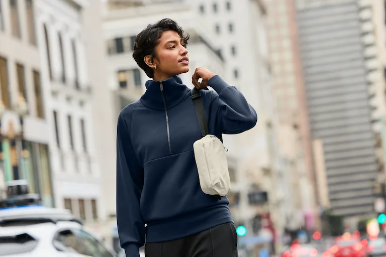 Woman wearing navy MiiR quarter zip pull over in urban setting